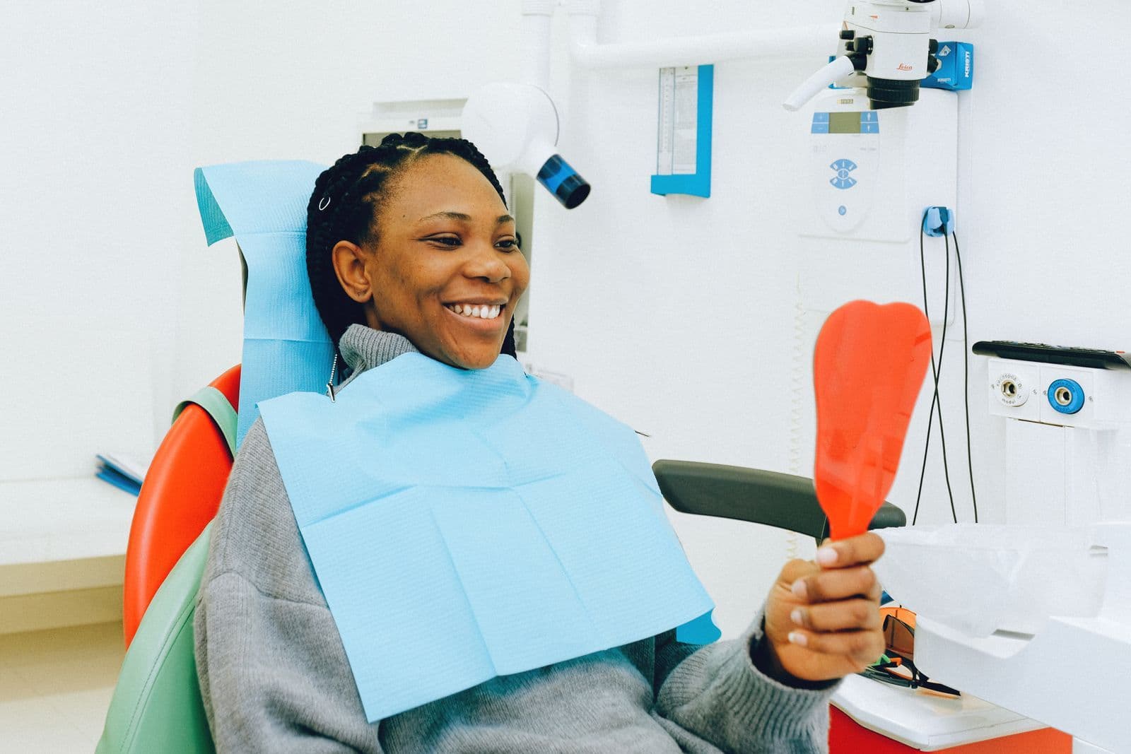 Smiling patient holding a mirror in the dental chair